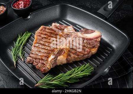 Frits sur une poêle à frire et os portreuse viande de bœuf Steak.Arrière-plan noir.Vue de dessus Banque D'Images