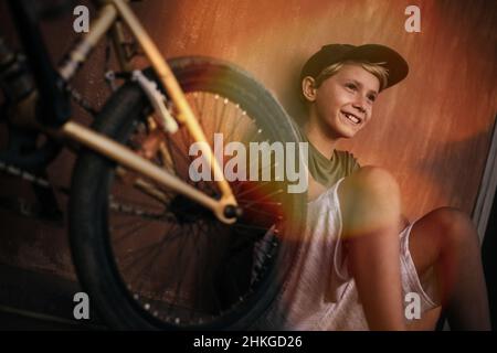 Beau garçon branché se reposant seul près de son vélo.Jeune homme souriant avec bmx heureux après avoir fait de la randonnée dans un parc de skate.Portrait d'un Banque D'Images