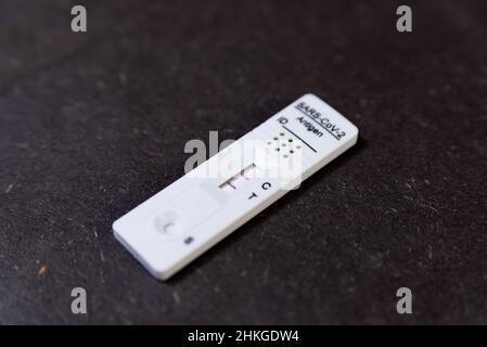 Un test Covid rapide de résultat positif, également connu sous le nom de test d'antigène ou de test de flux latéral, est vu dans un gros plan sur une table noire à Barcelone, Espagne le février Banque D'Images