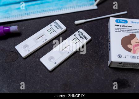 Un résultat positif test rapide Covid, également connu sous le nom de test d'antigène ou de flux latéral, est vu dans un gros plan sur une table noire avec un masque facial et la syrine Banque D'Images