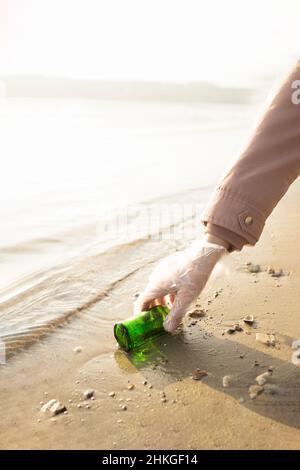 Faites du bénévolat pour prendre une bouteille de verre à la plage Banque D'Images