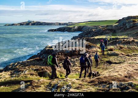 Marcheurs marchant d'Amlwch à Llaneilian le long du chemin côtier d'Anglesey avec vue le long de la côte rocheuse jusqu'à point Lynas. Île d'Anglesey, nord du pays de Galles, Royaume-Uni Banque D'Images