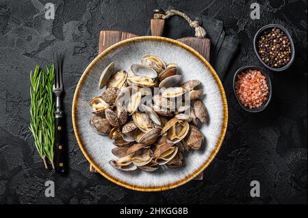 Les coquilles cuites à la vapeur clams vongole dans une assiette avec des herbes.Arrière-plan noir.Vue de dessus Banque D'Images