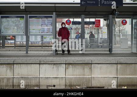 Une dame portant un masque Covid est debout dans une salle d'attente sur une plate-forme à la gare de Pasing à Munich.À côté d'elle le signe d'avertissement: Distance Banque D'Images