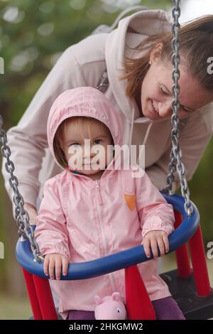 Fille en balancement avec mère dans le parc Banque D'Images