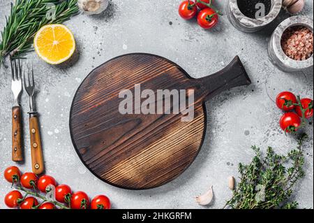 Cuisine et alimentation saine de fond avec planche à découper en bois et assaisonnements frais, herbes et légumes.Arrière-plan gris.Vue de dessus.Copier l'espace Banque D'Images