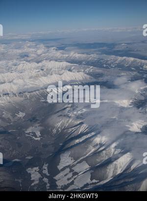 Vue sur les montagnes rocheuses enneigées du Canada entre l'Alberta et la Colombie-Britannique depuis le siège de fenêtre de l'avion lors d'hivers clairs vol de jour Banque D'Images