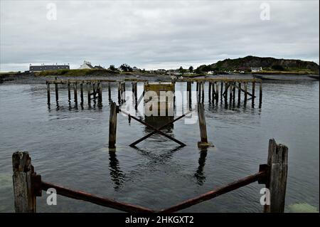 Une vue le long d'une jetée en bois ruiné sur l'île de Seil, qui donne sur l'île d'Easdale. Banque D'Images