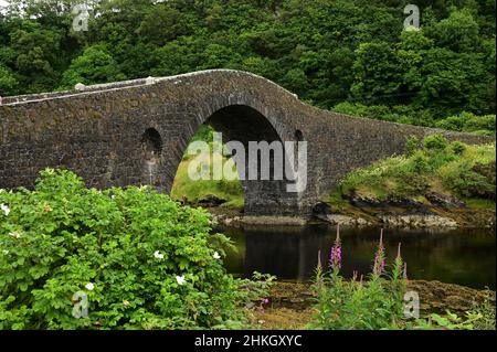 Vue sur l'ancien pont en pierre de l'Atlantique.Une étroite bande de l'océan Atlantique qui sépare l'Écosse continentale de l'île de Seil. Banque D'Images