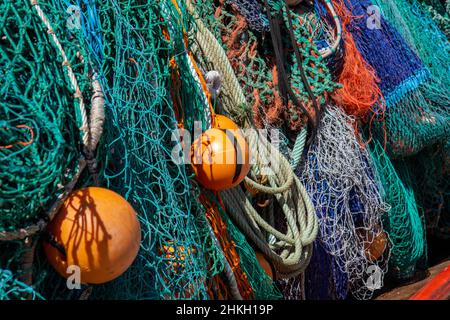 Gros plan de filets de pêche secs, flotteurs en plastique et corde de couleurs variées, turquoise, bleu, vert orange. Banque D'Images