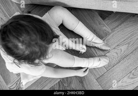 Jeune fille de 5 ans gcheeky mettant sur ses chaussures de ballet prêtes pour une classe de danse UK Banque D'Images