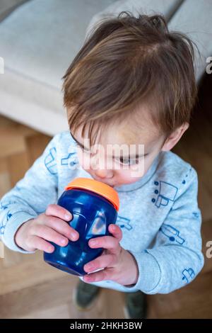 Jeune garçon de 2 ans qui apprécie une boisson saine d'eau dans un bécher Banque D'Images