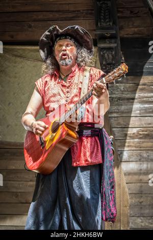 05 08 2021 Muskogee USA - Pirate dude en costume de guitare butming et de chant devant un arrière-plan en bois rugueux Banque D'Images