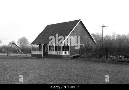 1950s, historique, extérieur, vue de face d'un pavillon sportif traditionnel de l'époque construit avec un cadre en bois sur une base en brique et un toit en pente.D'un point de vue architectural, avec une véranda couverte ou une véranda à l'avant, ces types de bâtiments d'un étage situés en bordure des terrains de sport ont été vus dans de nombreux terrains de loisirs et de sport en Grande-Bretagne à l'heure actuelle, offrant des vestiaires pour les sports d'équipe tels que le cricket, le rugby et le football.À côté de ce pavillon récemment construit à Witney, Oxford, Angleterre, Royaume-Uni, une aire de jeu de chlldrens, avec toboggan de médaille. Banque D'Images