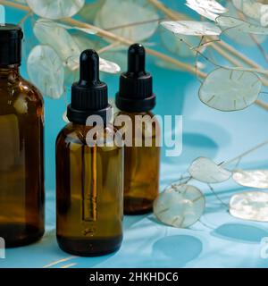 Flacons avec pipettes en verre gros plan. flacon en verre mockup huile essentielle ou sérum cosmétique sur fond bleu.Bouteille cosmétique en verre brun. Banque D'Images