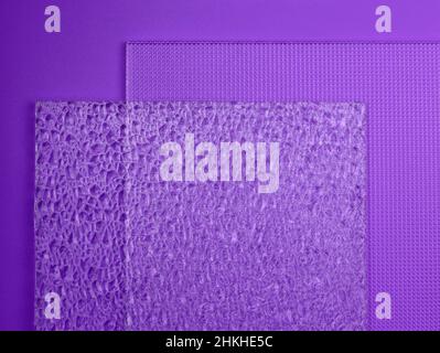 Vue de dessus en verre gaufré sur un arrière-plan violet.Deux échantillons de différents verres texturés.Gros plan gaufré transparent en verre. Banque D'Images