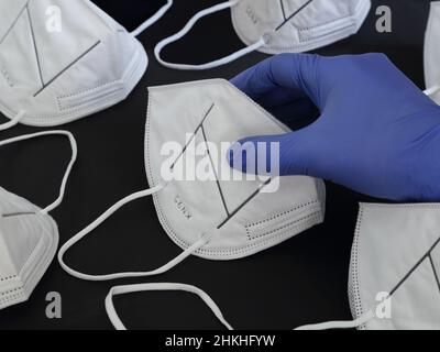 Une main portant des gants en caoutchouc nitrile bleu prend un masque d'une réserve de KN95 masques de protection contre la poussière. Banque D'Images