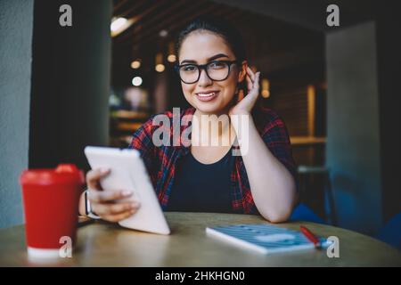 Femme joyeuse indépendante avec tablette dans le café Banque D'Images