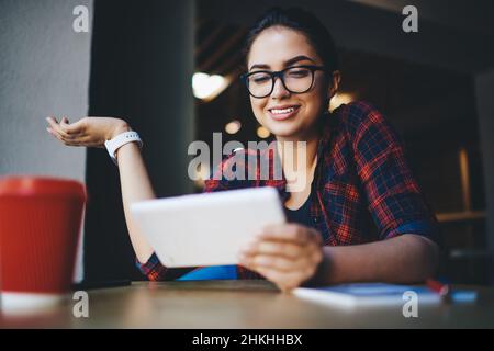 Une femme positive qui navigue sur une tablette tout en travaillant à distance dans un café Banque D'Images