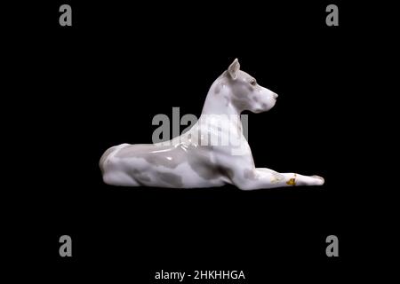 Un chien de la race Great Dane blanc est isolé sur fond noir. Figurine en porcelaine.Photo de haute qualité Banque D'Images