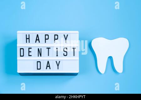 Bonne journée internationale du dentiste.Maquette en papier de dent et d'outil dentaire sur fond bleu.Concept de soins dentaires.Carte de vœux pour les vacances professionnelles Banque D'Images