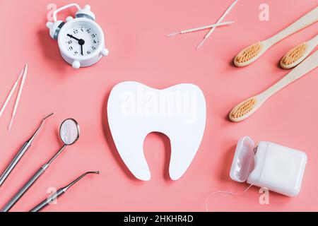 Concept de soins dentaires.Outils dentaires sur fond rose.Bonne journée chez le dentiste.Maquette de la dent coupée en papier.Copier l'espace. Banque D'Images