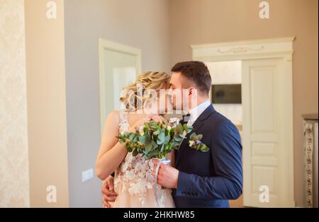 Beau mariage, mari et femme, mariée et marié debout dans le loft intérieur près de la fenêtre.Couple de jeunes mariés amoureux.Le marié embrasse la mariée par le shoul Banque D'Images