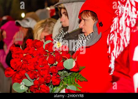 Un fan de football de Crimson Tide tient un bouquet de roses alors qu'elle attend pour féliciter l'équipe du Championnat national de Tuscaloosa, Alabama. Banque D'Images