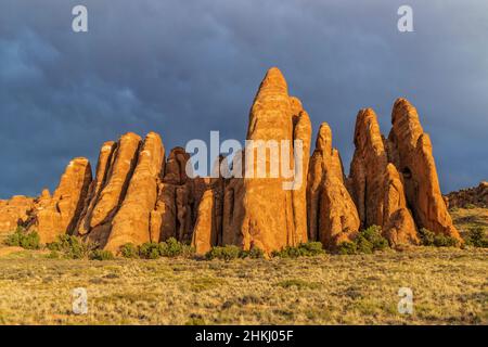 Nageoires rouges ensoleillées contre un ciel sombre rappelant Stonehenge à Sand Dune Arch dans le parc national d'Arches près de Moab, Utah. Banque D'Images