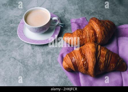Croissants frais et tasse de café sur fond de marbre foncé. Banque D'Images