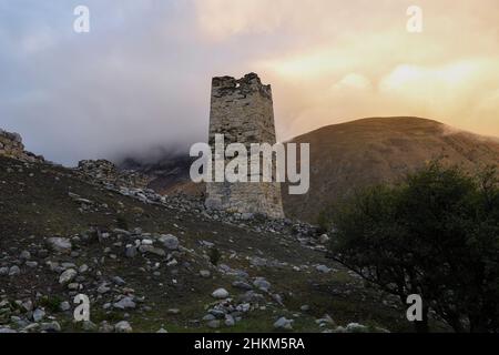 Une vieille tour de bataille d'Ossétie contre le fond du coucher de soleil dans les montagnes brumeuses.Verhniy Fiagdon.Ossétie du Nord, Russie Banque D'Images