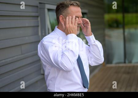 Homme âgé en détresse ou anxieux levant les mains sur les côtés de sa tête alors qu'il se trouve sur un passage souterrain urbain Banque D'Images