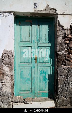 Porte en bois vert sur la construction typique de la maison canarienne avec le rendu cassé pour révéler la construction de roche volcanique Teguise Lanzarote îles Canaries SPAI Banque D'Images