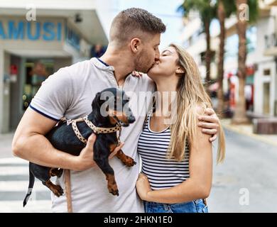 Jeune couple caucasien embrassant et embrassant debout avec chien à la ville. Banque D'Images