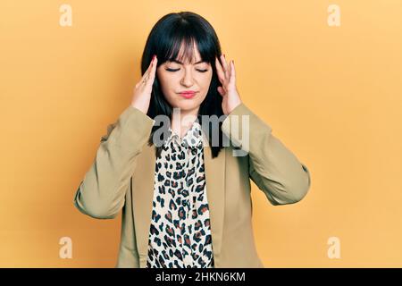 Jeune femme hispanique portant des vêtements d'affaires souffrant de maux de tête désespérés et stressés parce que la douleur et la migraine. Mains sur la tête. Banque D'Images