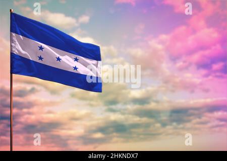 Le drapeau du Honduras se déforme avec l'endroit pour votre texte sur fond ciel nuageux et coloré. Banque D'Images