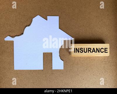 Texte d'assurance sur bloc de bois avec fond de maison modèle brûlé.Concept d'assurance. Banque D'Images