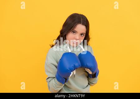 portrait d'enfant sérieux en gants de boxe sur fond jaune Banque D'Images