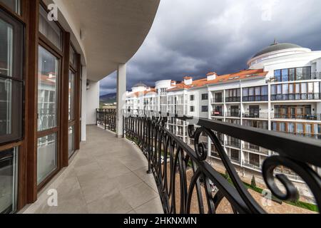 Un grand balcon incurvé d'un bâtiment de plusieurs étages avec des rails en métal noir en fer forgé avec des motifs.Le balcon offre une vue sur les maisons du Banque D'Images