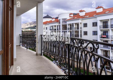 Un grand balcon incurvé d'un bâtiment de plusieurs étages avec des rails en métal noir en fer forgé avec des motifs.Le balcon offre une vue sur les maisons du Banque D'Images