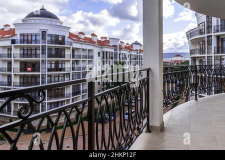 Un grand balcon incurvé d'un bâtiment de plusieurs étages avec des rails en métal noir en fer forgé avec des motifs.Le balcon offre une vue sur les maisons du Banque D'Images