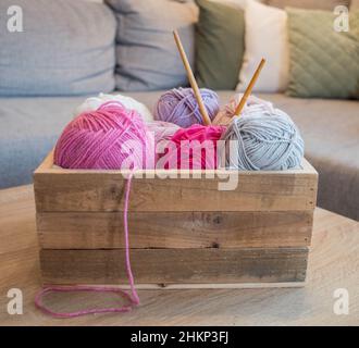 balles de laine colorées dans une boîte en bois avec aiguilles en bambou à tricoter faites à la main Banque D'Images