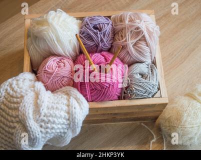 balles de laine colorées dans une boîte en bois avec aiguilles en bambou à tricoter faites à la main Banque D'Images