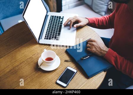 Crop homme entrepreneur utilisant ordinateur portable dans le café Banque D'Images