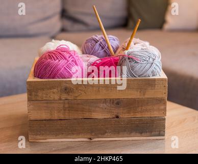 balles de laine colorées dans une boîte en bois avec aiguilles en bambou à tricoter faites à la main Banque D'Images