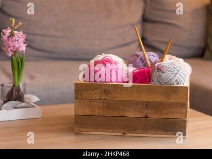 balles de laine colorées dans une boîte en bois avec aiguilles en bambou à tricoter faites à la main Banque D'Images