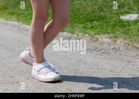 Anonyme non reconnaissable enfant d'âge scolaire élémentaire marchant sur la route en portant des pieds de sport velcro générique ferme-pieds, une personne, été extérieur Banque D'Images