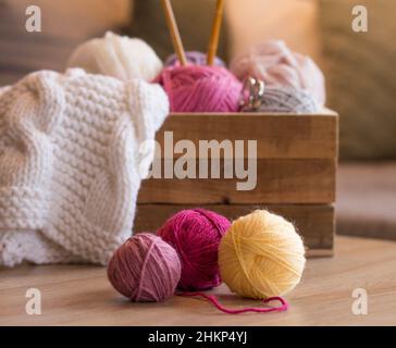 boules de laine en face d'une boîte en bois avec aiguilles en laine et bambou à tricoter faites à la main Banque D'Images