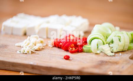 Fromage, poireau, piment et ail sur une planche à découper. Banque D'Images