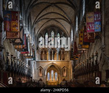 Dublin, Irlande, août 2019 drapeaux et fanions sur les deux côtés de l'autel illuminé dans la cathédrale Saint-Patrick avec arches et vitraux Banque D'Images